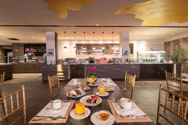 Frühstücksbereich des A.Roma Lifestyle Hotels mit gedecktem Tisch und Getränken.