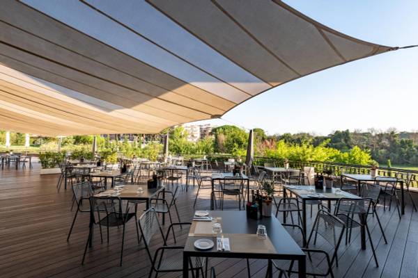 Terrasse des A.Roma Lifestyle Hotels mit Tischen und Stühlen unter einem Sonnensegel