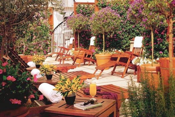 Terrasse des Dei Mellini Hotels mit Holzliegen, Pflanzen und einem Glas Orangensaft