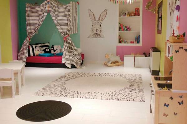 Ein buntes Kinderzimmer mit einem Bett, einem großen Teppich und Spielzeug.