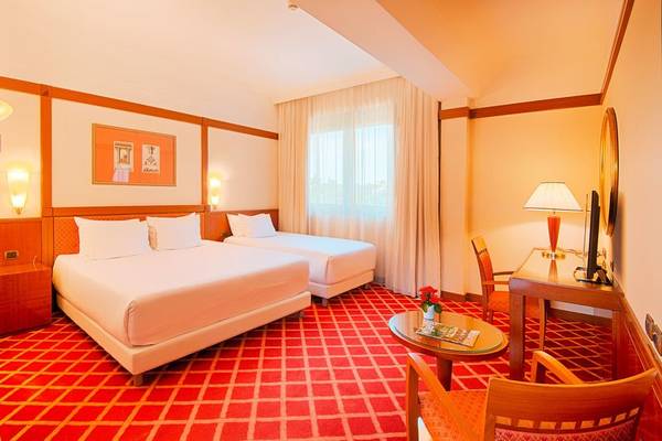 Doppelzimmer im NH Roma Villa Carpegna Hotel mit zwei Betten, Tisch, Stühlen und Dekor.