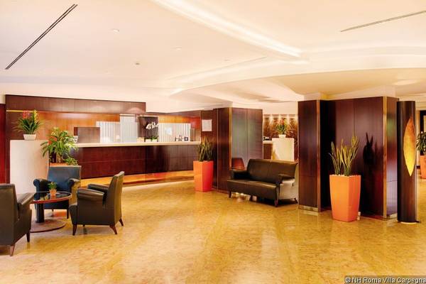 Lobby des NH Roma Villa Carpegna Hotels mit Rezeption, Sofas, Sesseln und Pflanzen