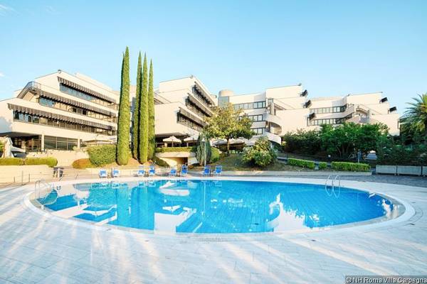 Außenbereich des NH Roma Villa Carpegna Hotels mit Swimmingpool und Sonnenliegen