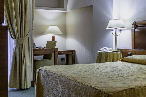 Schlafzimmer im Pineta Palace Hotel mit Bett, Schreibtisch und Lampen.