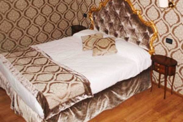 Schlafzimmer im Tre Archi Hotel mit viktorianischem Stil, goldenem Bett und braunen Wandverkleidungen.