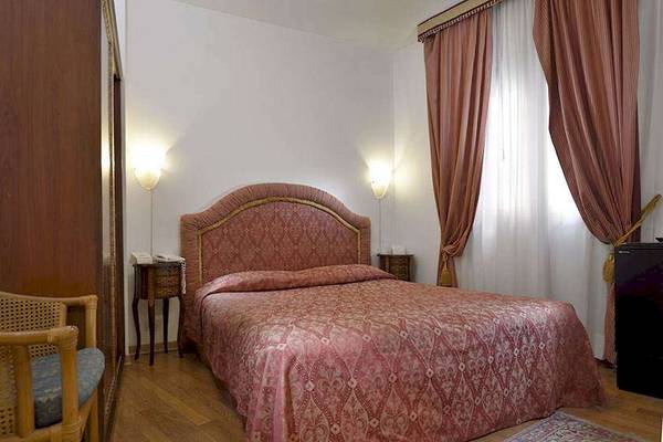 Ein Schlafzimmer im San Marco Palace Hotel mit einem rosa Bett, Nachttischen und Lampen.