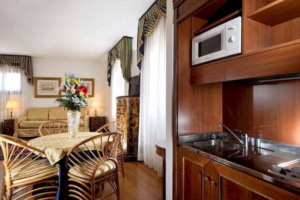 Innenansicht eines Zimmers im San Marco Palace Hotel mit Tisch, Stühlen, Sofa und Küche.