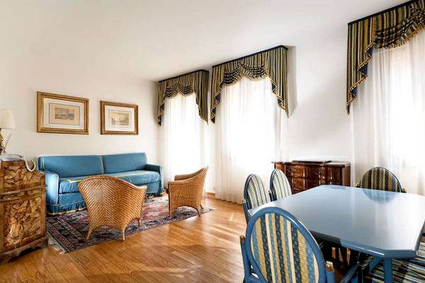 Wohnzimmer im San Marco Palace Hotel mit blauem Sofa, Esstisch und Stühlen.