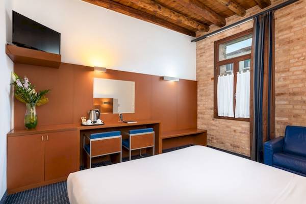 Eurostars Residenza Cannaregio Hotelzimmer mit Fernseher, Schreibtisch, Stühlen und Sofa.