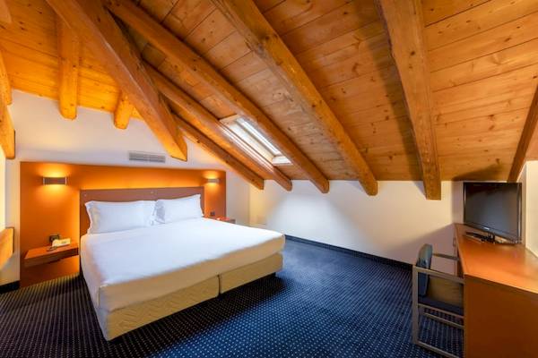 Hotelzimmer im Eurostars Residenza Cannaregio mit Doppelbett, Fernseher, Schreibtisch und gemauerter Wand.