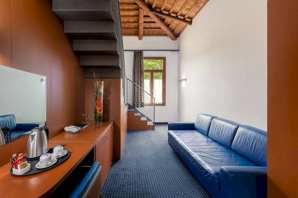 Innenansicht des Eurostars Residenza Cannaregio Hotels mit blauer Couch, Schreibtisch und Treppe.