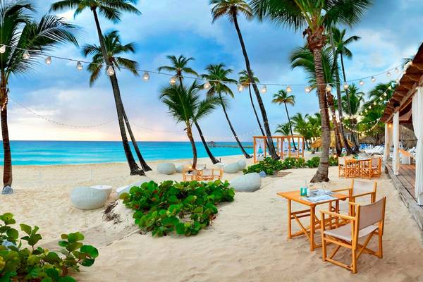 Nachtansicht des Catalonia Bayahibe Strandes mit leuchtenden Lichterketten und Tischen im Freien.