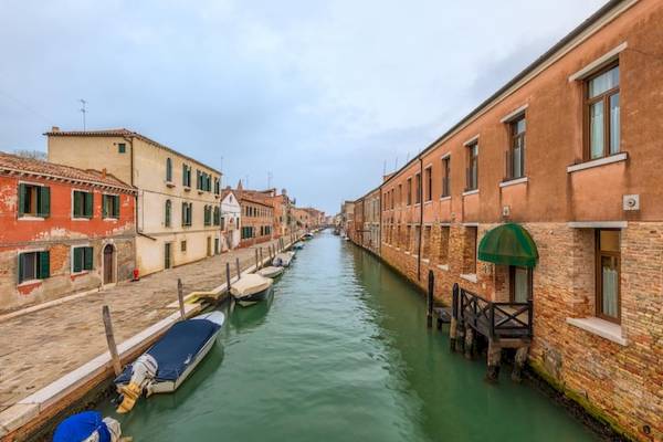 Ein Kanal in Venedig mit mehreren Booten und alten Gebäuden an beiden Seiten.