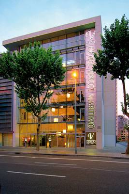 Außenansicht des Vincci Maritimo Hotels mit großer Glasfassade und Bäumen vor dem Gebäude.