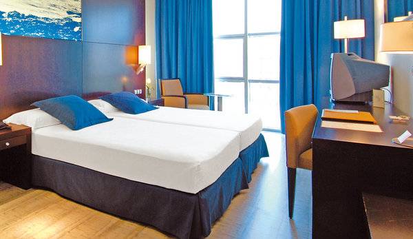 Doppelbettzimmer im Vincci Maritimo Hotel mit blauer Bettwäsche und modernen Möbeln.