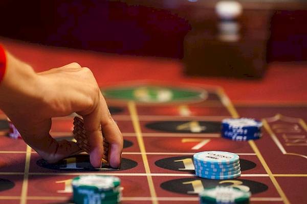Eine Person spielt an einem Casino-Tisch mit verschiedenen Spielchips und Spielmarken.
