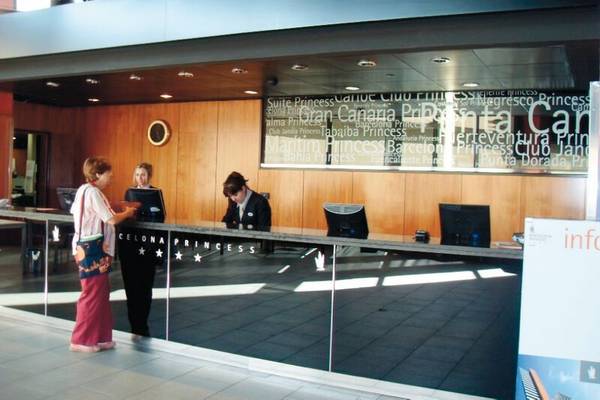 Empfangsbereich des Barcelona Princess Hotels mit zwei Frauen an der Rezeption und einer Informationstafel.
