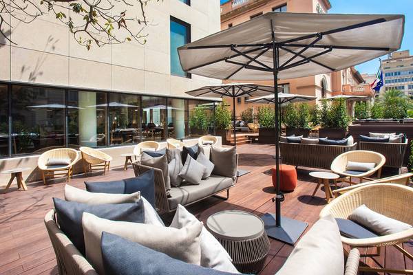 Terrasse des Ocean Drive Barcelona Hotels mit Sonnenschirmen, Sofas und Tischen.