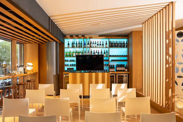 Innenraum des Ocean Drive Barcelona Hotels mit weißen Stühlen und einer Bar im Hintergrund.