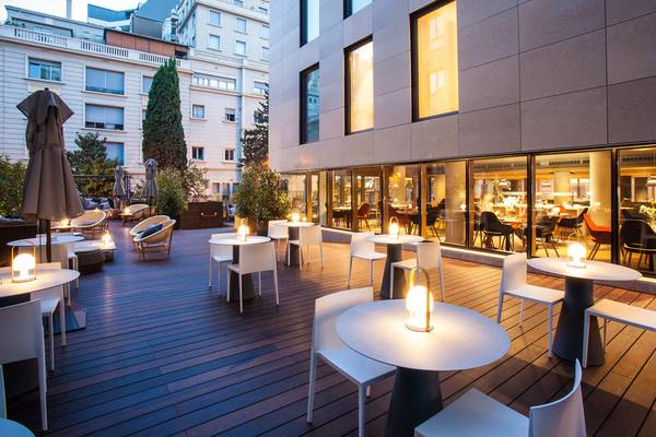 Außenterrasse des Ocean Drive Barcelona Hotels mit weißen Tischen und Stühlen und leuchtenden Tischlampen.