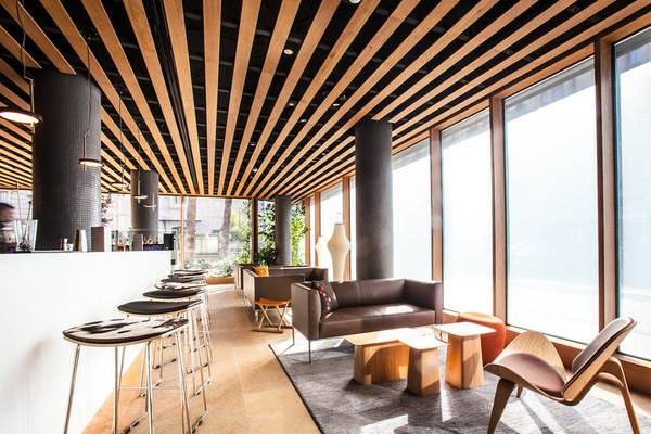 Innenraum des Ocean Drive Barcelona Hotels mit modernen Möbeln, großen Fenstern und hölzerner Decke.