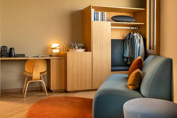 Innenansicht eines Zimmers im Ocean Drive Barcelona Hotel mit Schreibtisch, Stuhl, Couch und Garderobe.