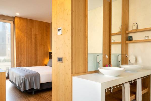 Innenansicht eines Zimmers im Hotel Ocean Drive Barcelona mit einem Bett, Badezimmer und Holzboden.