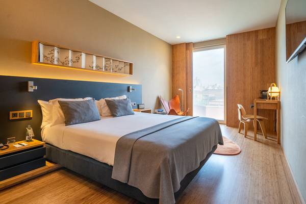 Ein modernes Hotelzimmer von Ocean Drive Barcelona mit Holzboden, Bett, Schreibtisch und Ausblick.