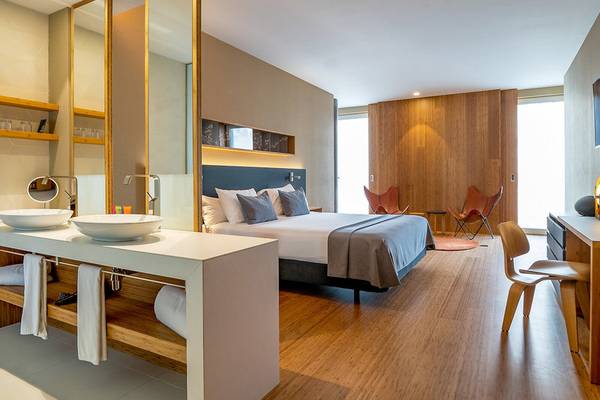 Innenansicht eines Schlafzimmers im Ocean Drive Barcelona Hotel mit Bett, Schreibtisch, Stühlen und Badezimmer.