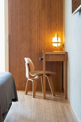 Zimmer mit Holzwand und Holzschreibtisch und Lampe im Ocean Drive Barcelona Hotel