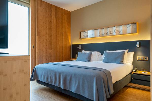 Ein elegantes Hotelzimmer im Ocean Drive Barcelona mit einem großen Bett, Holzboden und modernen Möbeln.