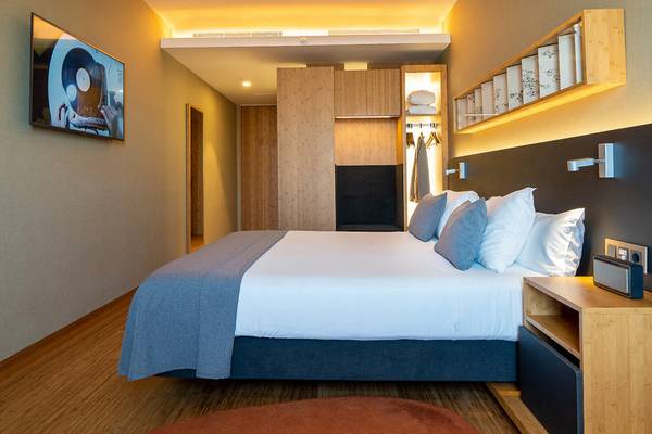Innenansicht eines Hotelzimmers im Ocean Drive Barcelona mit Bett, Nachttischen und Fernseher.