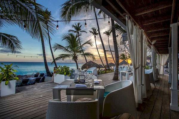 Terrasse des Hotels Catalonia Bayahibe mit Blick auf das Meer bei Sonnenuntergang.