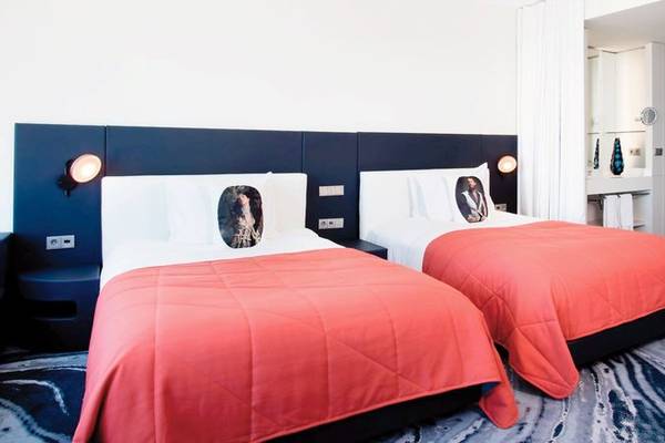Doppelbett-Zimmer im W Barcelona Hotel mit roten Decken und weißen Kissen mit Bilddruck.