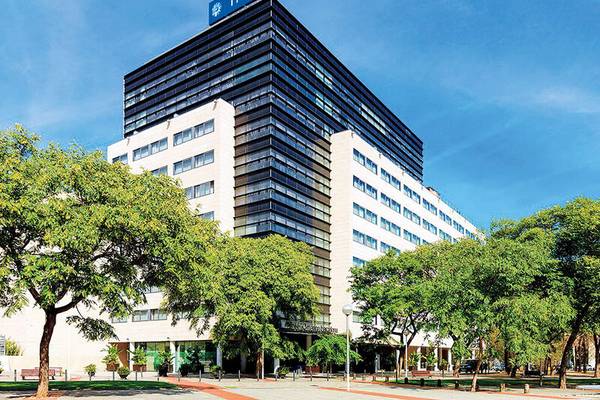 Außenansicht des H10 Marina Barcelona Hotels mit vielen Fenstern und umgeben von Bäumen.