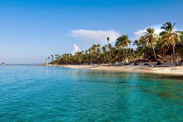 Sonnenuntergang am Strand von Bayahibe mit blauem Wasser und grünen Palmen