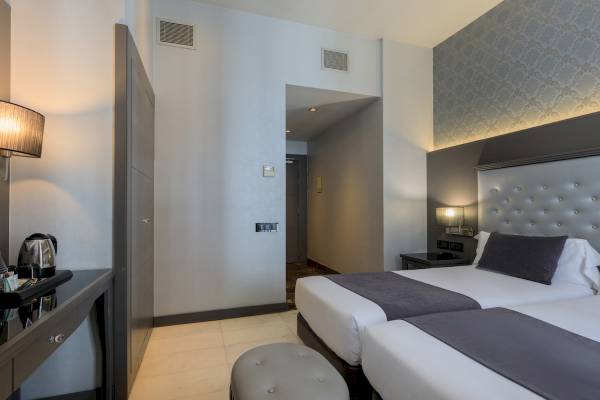 Hotelzimmer im Ciutadella Barcelona mit zwei Betten, Nachttischen und Deko.