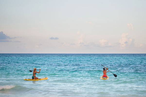 Zwei Personen auf Stand-Up-Paddleboards im Meer vor dem Catalonia Bayahibe Hotel.