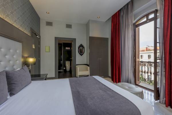 Schlafzimmer im Ciutadella Barcelona Hotel mit Bett, Nachttisch, Stuhl und offenem Balkon.