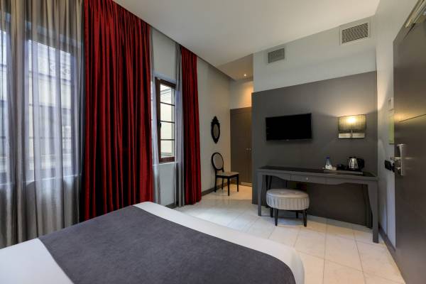 Hotelzimmer im Ciutadella Barcelona mit Bett, Schreibtisch, Fernseher und Stuhl.