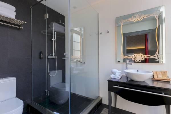 Badezimmer im Ciutadella Barcelona Hotel mit Glasdusche, Waschbecken und Spiegel.