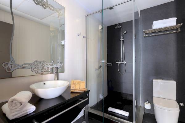 Badezimmer im Ciutadella Barcelona Hotel mit Glasdusche, Waschbecken und Toilette.