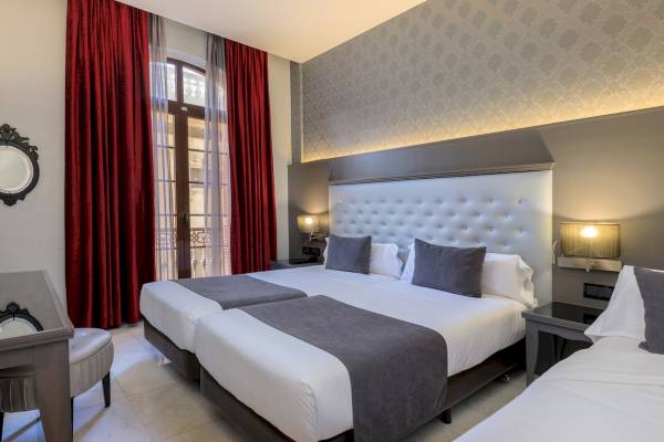 Doppelbett-Zimmer im Ciutadella Barcelona Hotel mit rotem Vorhang und Nachttischen