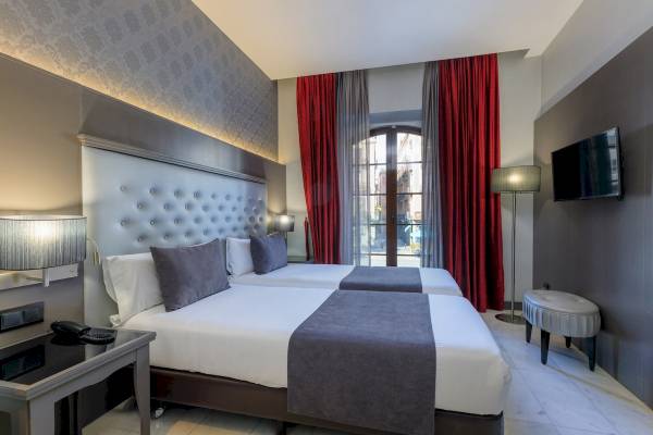 Zweibettzimmer im Hotel Ciutadella Barcelona mit zwei Betten, modernen Lampen und Fernseher.