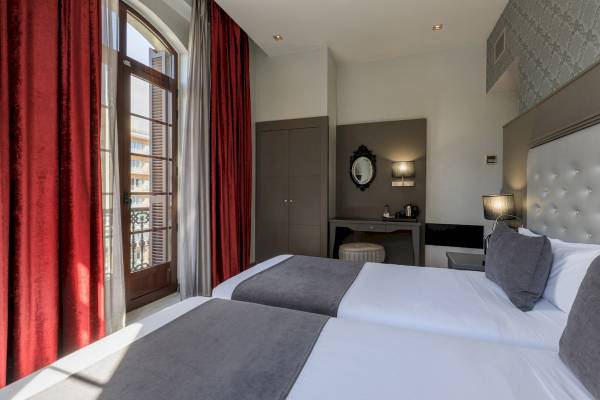 Doppelzimmer im Ciutadella Barcelona Hotel mit zwei Betten, grauen Kissen und weißen Laken.