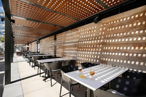 Terrasse des HCC St. Moritz Hotels mit Tischen, Stühlen und Sonnenschutz.