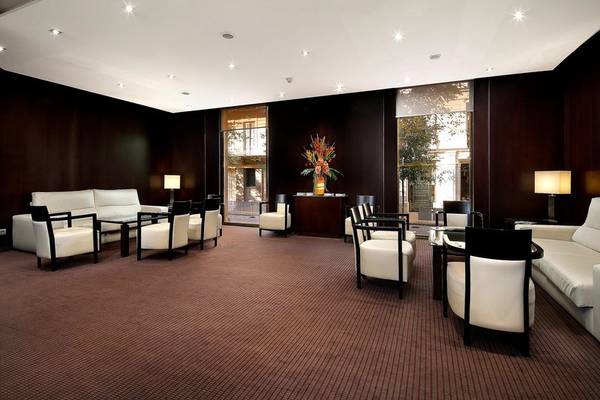 Innenansicht der Lobby im HCC St. Moritz Hotel mit weißen Sofas, schwarzen Stühlen und einem zentralen Blumenarrangement.