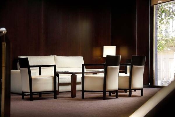 Lounge-Bereich im HCC St. Moritz Hotel mit weißen Sofas, schwarzen Stühlen und Glastisch.