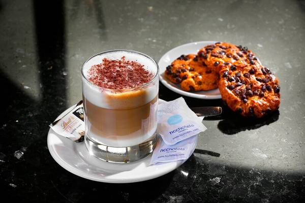 Eine Tasse Kaffee und zwei Kekse auf einem Tablett im HCC St. Moritz Hotel.