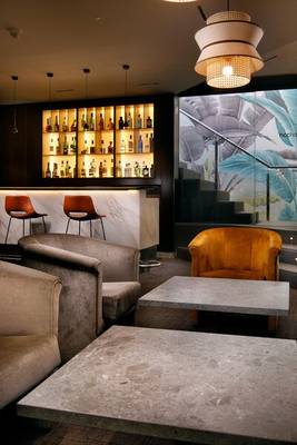 Loungebereich im HCC St. Moritz Hotel mit Bar, Sofas und hängenden Lampen.